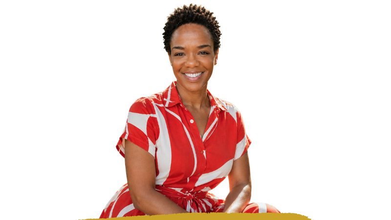 Stephanie Willis, smiling, seated, in a red and white patterned dress
